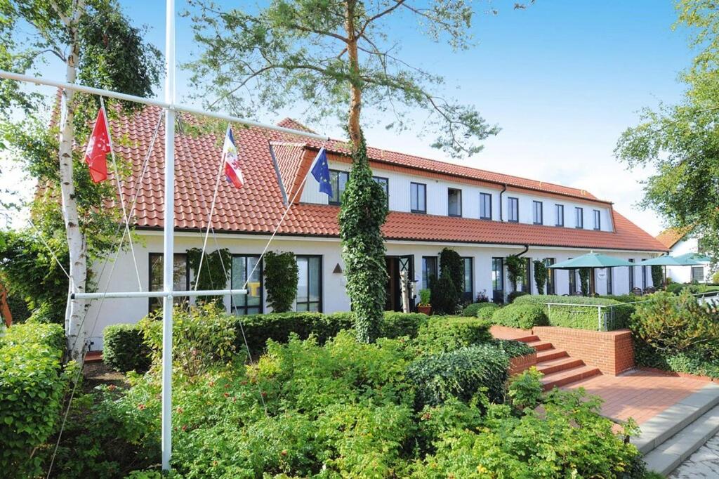 um edifício com um telhado vermelho e alguns arbustos em Apartments Post Hiddensee, Vitte em Vitte