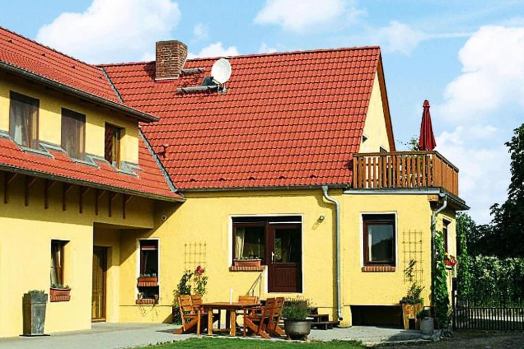 a yellow house with a red roof and a table at Apartment, Beetzseeheide in Ketzür