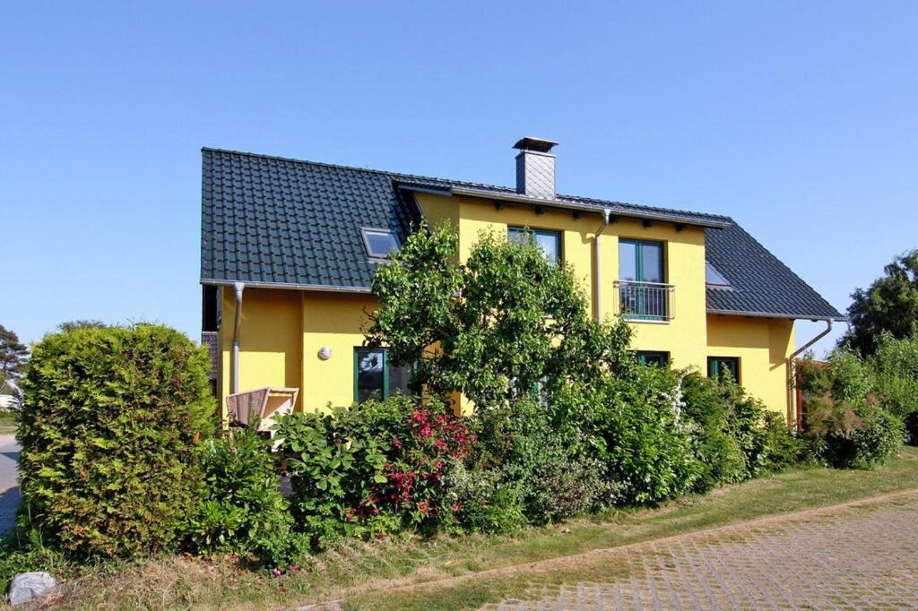 a yellow house with bushes in front of it at Doppelhaushälfte mit Blick auf das Wasser am Hafen von Neuendorf in Neuendorf
