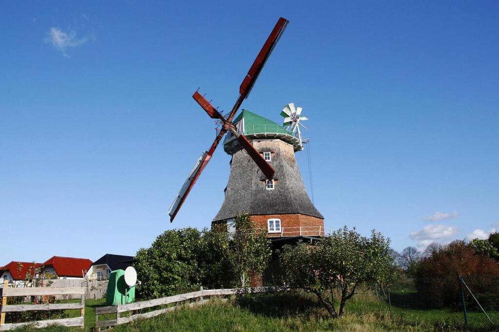 un molino de viento en la cima de una colina con una valla en Holländer Windmühle in Neubukow, en Neubukow