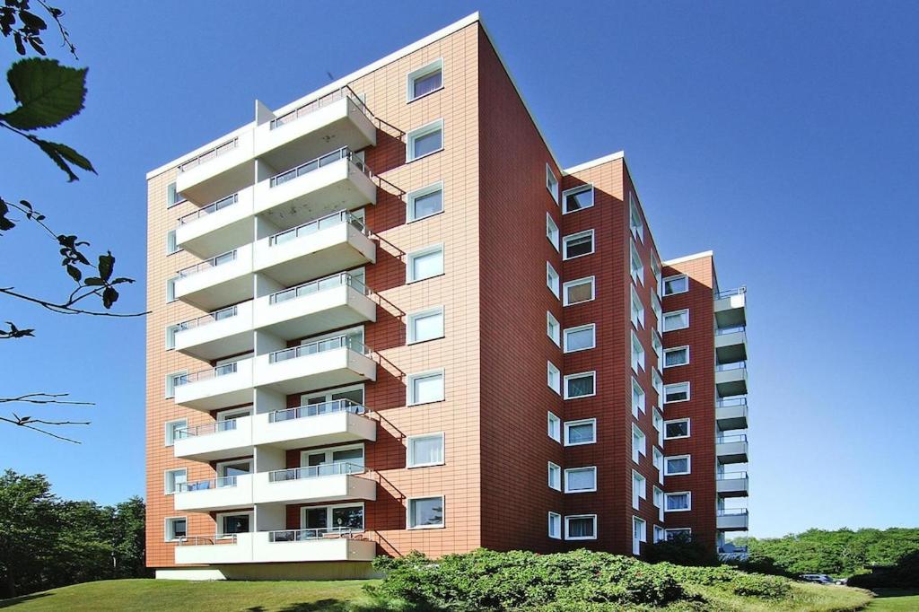 un edificio alto de color rojo con balcones blancos en Apartment, St Peter-Ording, en Sankt Peter-Ording