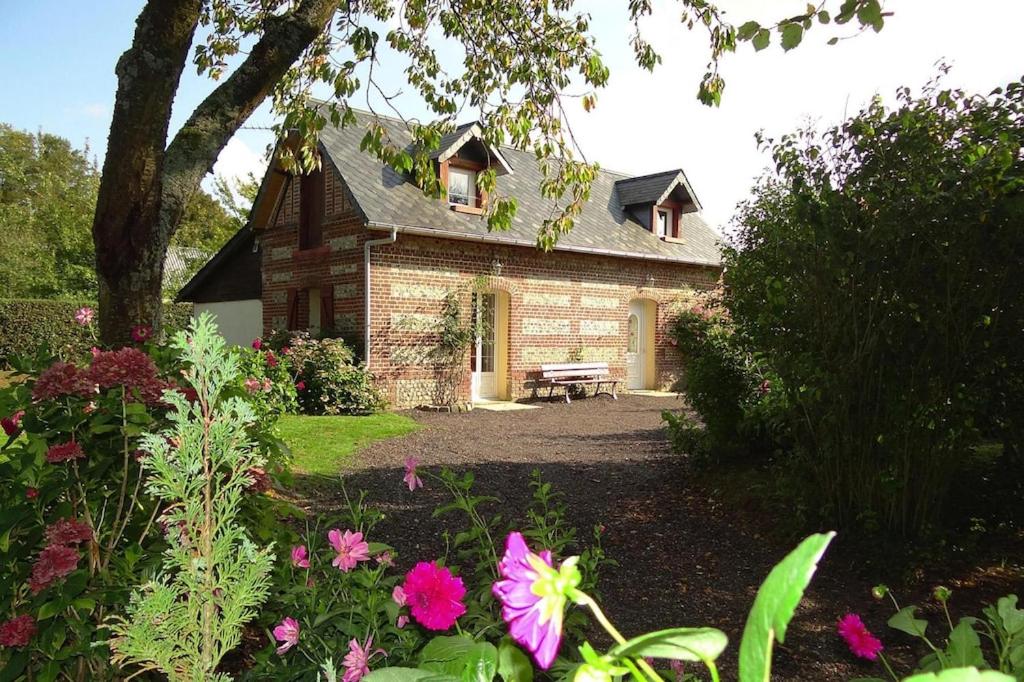 ein Backsteinhaus mit einer Bank im Garten in der Unterkunft Cottage, Les Grandes Ventes in Les Grandes-Ventes