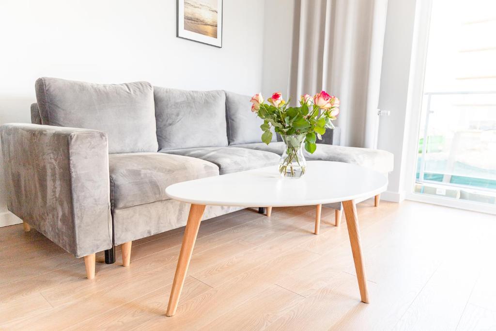 a living room with a couch and a table with flowers at AL-DOM apartamenty Apartament Stjarne in Kołobrzeg