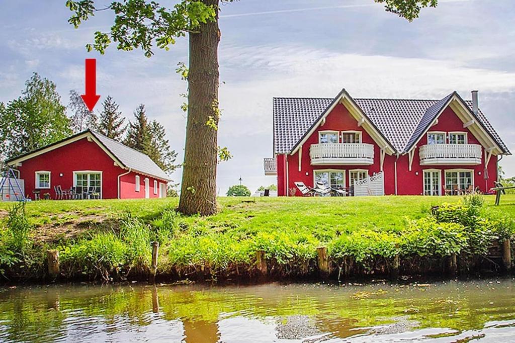 a red house next to a tree next to a river at Vacation home Spreeidyll, Schlepzig in Schlepzig
