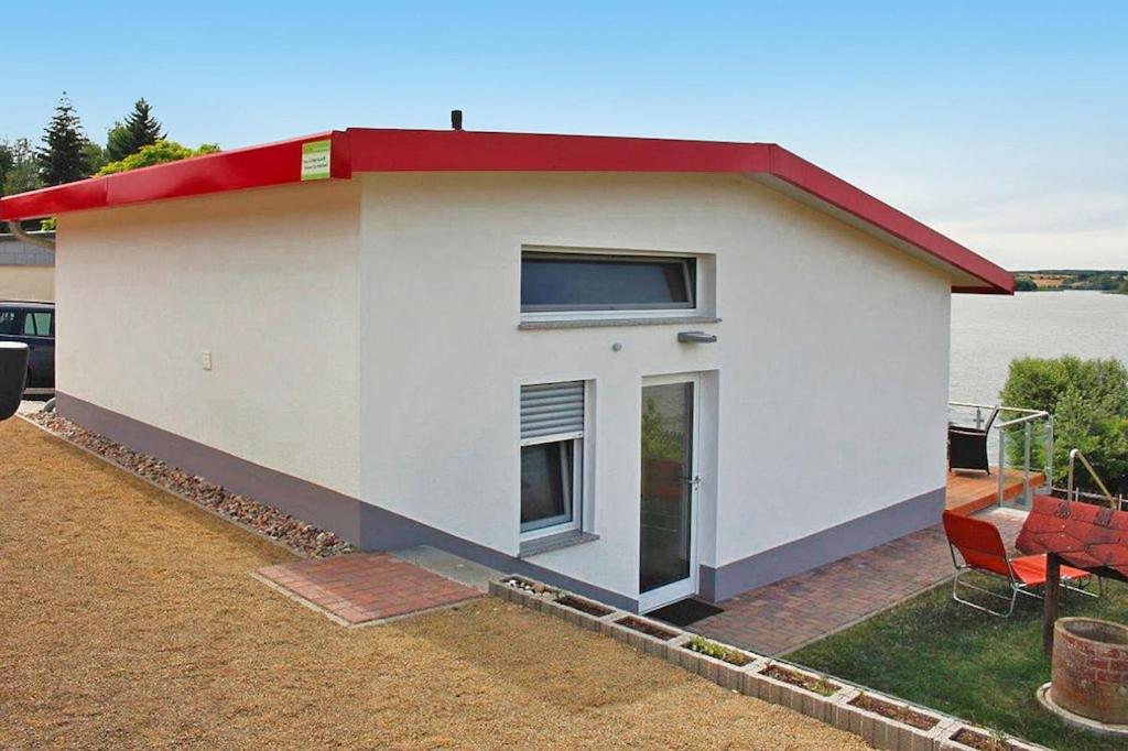 uma pequena casa branca com um telhado vermelho em Holiday home Seeblick, Fürstenwerder em Fürstenwerder