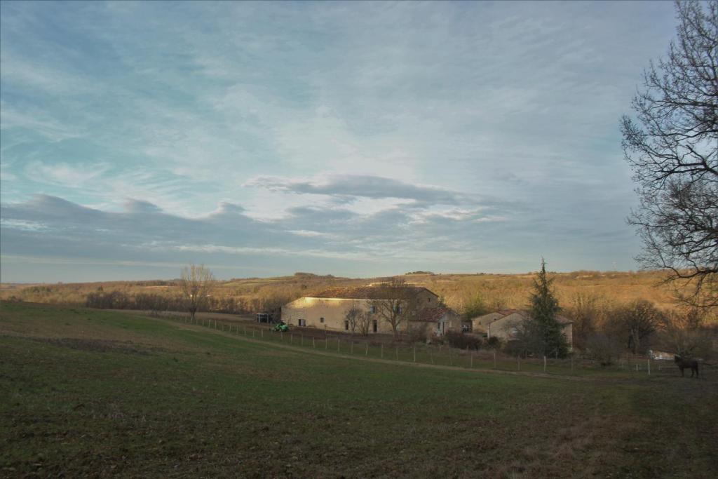 un champ avec une clôture et une grange au loin dans l'établissement Domaine de la Couderquié, à Lautrec