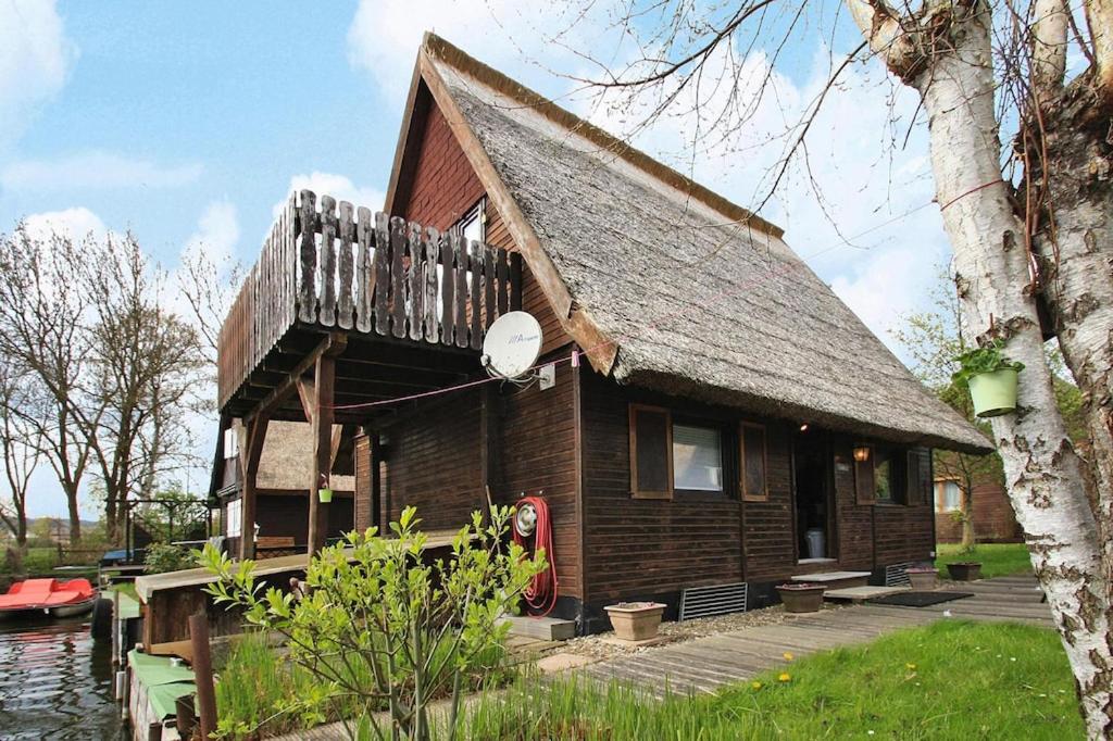 a small wooden house with a porch on a lake at Boathouse, Teterow in Teterow