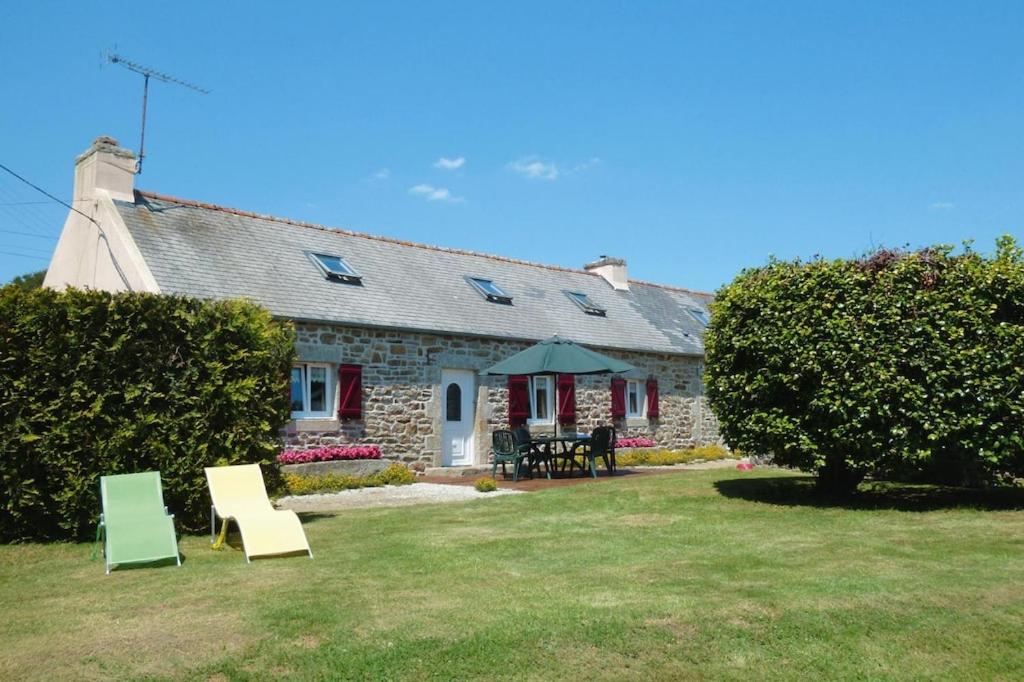 une maison en pierre avec des chaises dans la cour dans l'établissement Cottage, Plogonnec, à Plogonnec