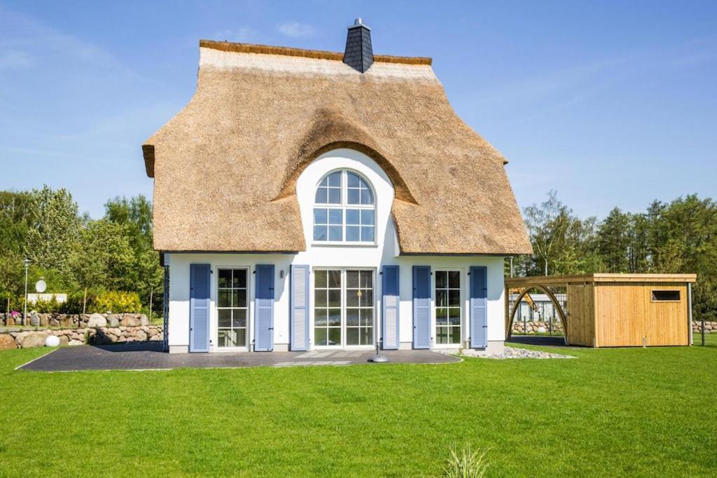 a thatched roof house with a green lawn at Holiday house, Fuhlendorf in Fuhlendorf