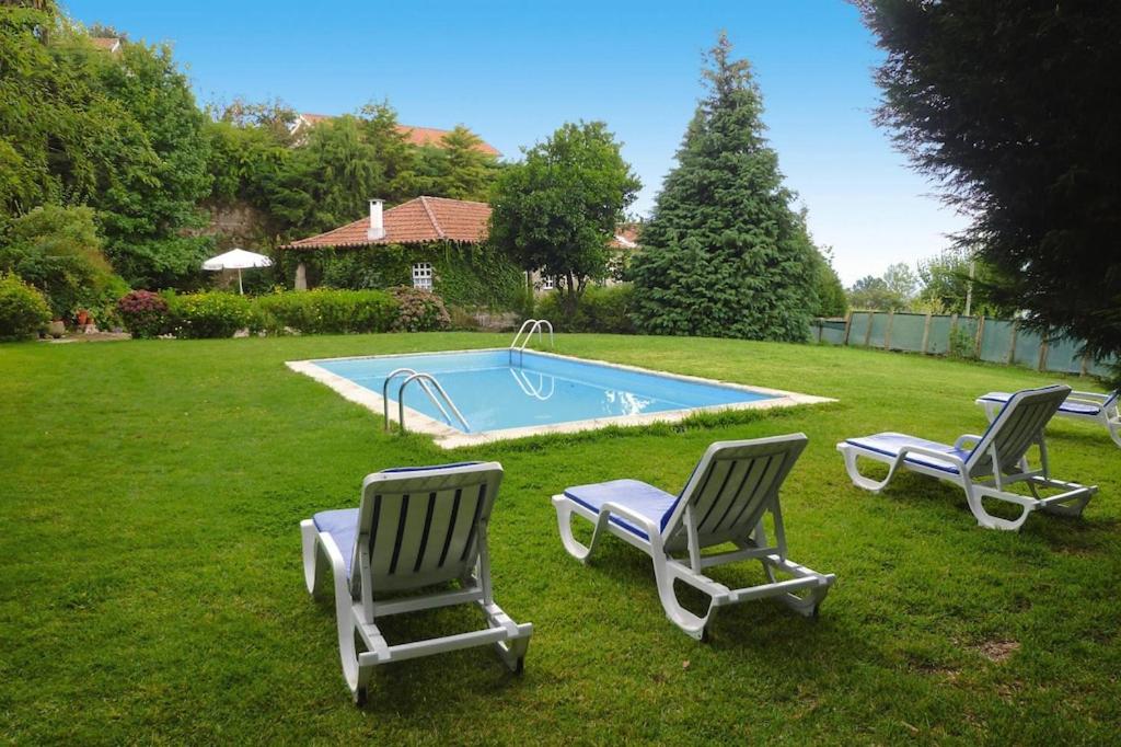 drie ligstoelen en een zwembad in de tuin bij holiday home, Folhada in Marco de Canavezes