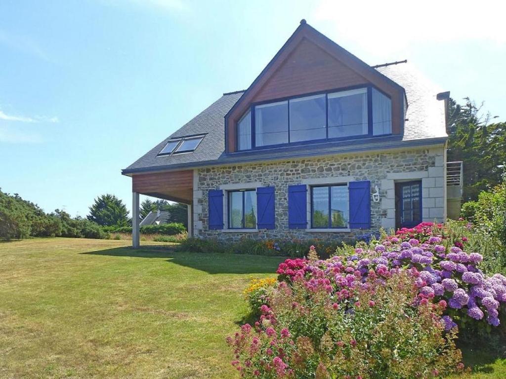 een huis met blauwe ramen en bloemen in de tuin bij Holiday home with sea view, Pordic in Pordic