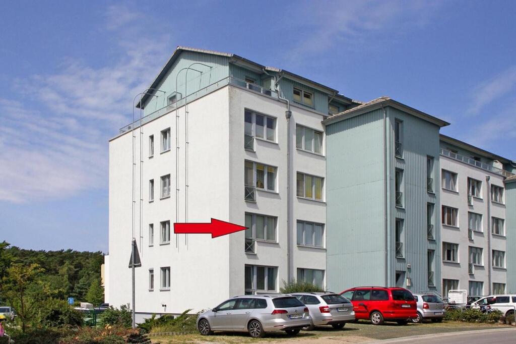 un grand bâtiment blanc avec une flèche rouge dans l'établissement Apartment, Zinnowitz, à Zinnowitz