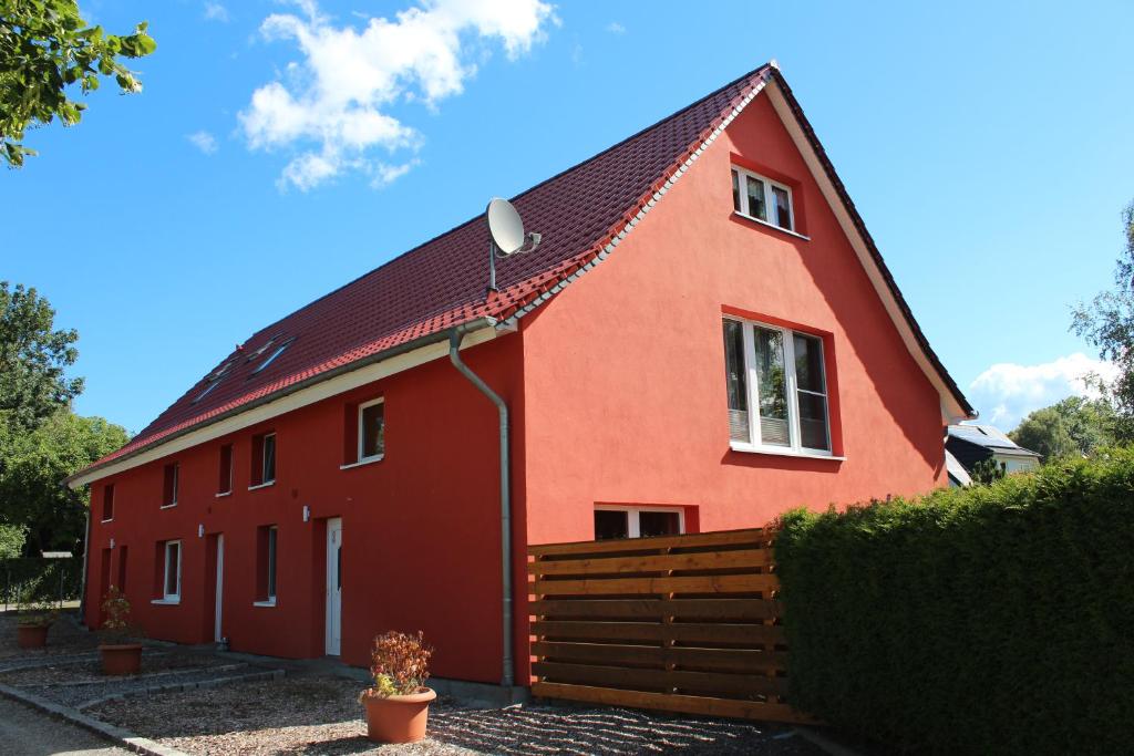 een rood huis met een hek ervoor bij Zum Kranichblick FeWo 1&2 in Niepars