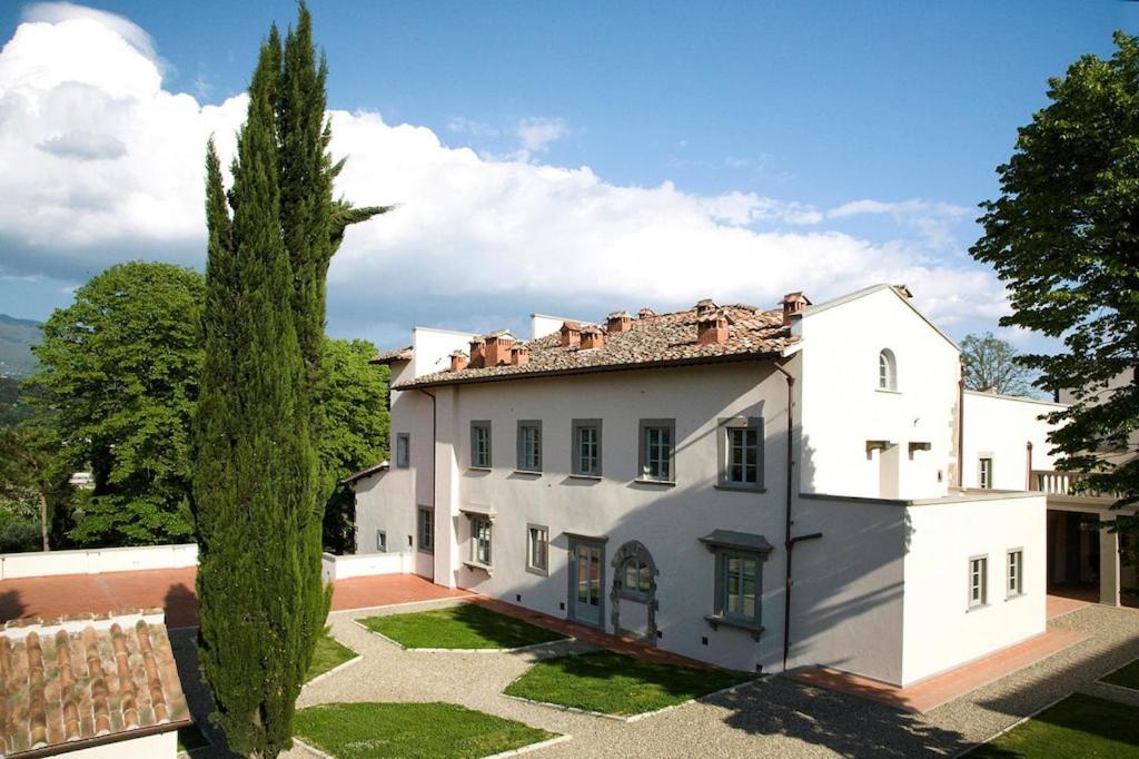 ein großes weißes Haus mit einem Baum davor in der Unterkunft Residence Villa Il Palagio, Rignano sull" Arno in Rignano sullʼArno