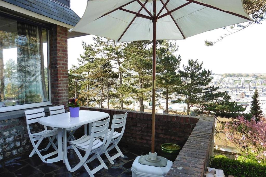 un patio avec une table, des chaises et un parasol dans l'établissement Duplex in Fécamp with Harbor Views, à Fécamp