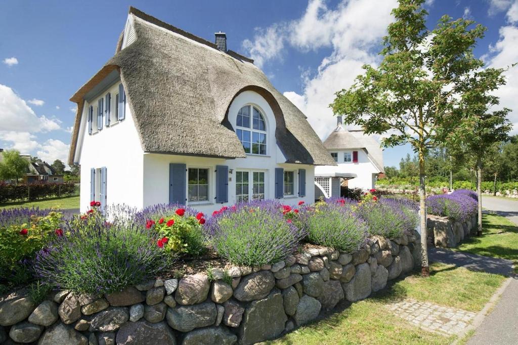 a cottage with a thatched roof and a stone wall at Holiday house, Fuhlendorf in Fuhlendorf