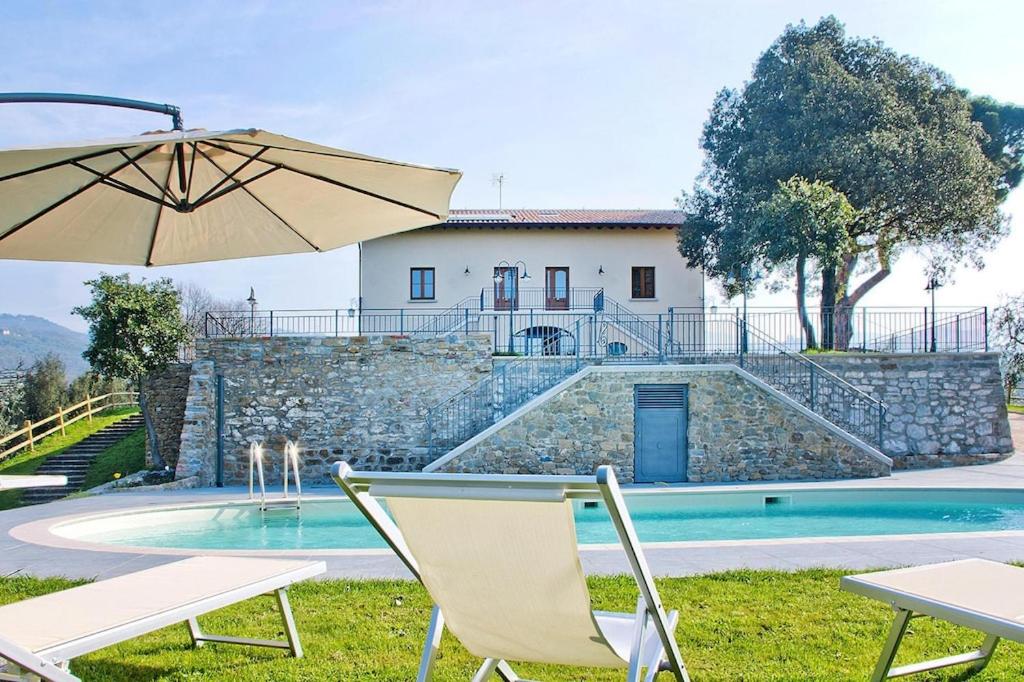 una mesa con sillas y una sombrilla junto a la piscina en Agriturismo Giugnano Poggio del Sole Lamporecchio, en Lamporecchio