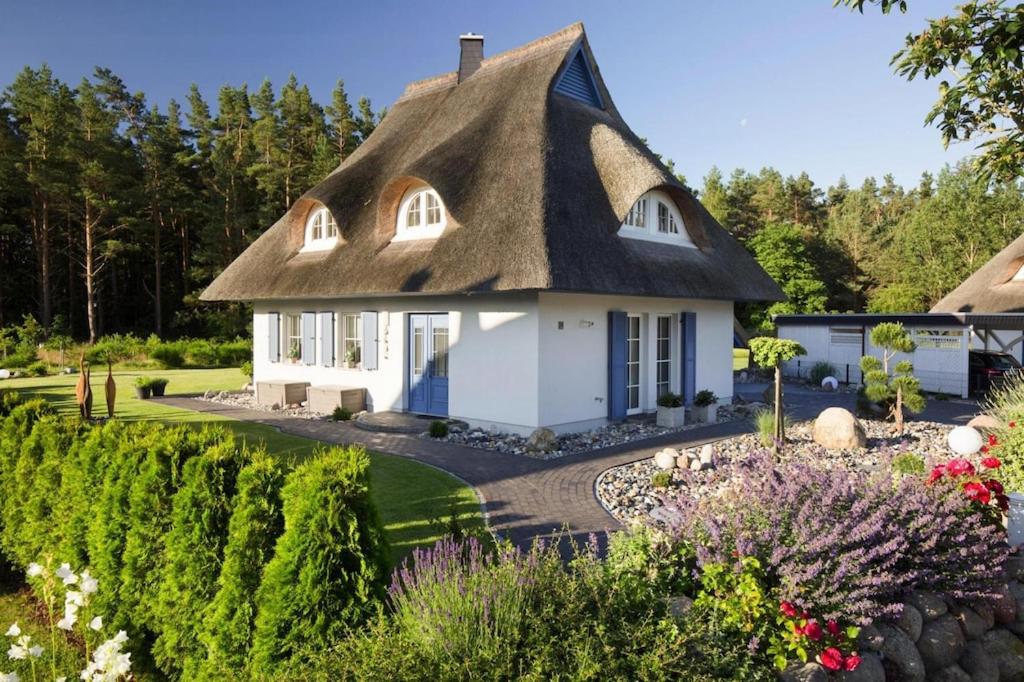 a thatch roof house with a garden and flowers at Holiday house, Fuhlendorf in Fuhlendorf