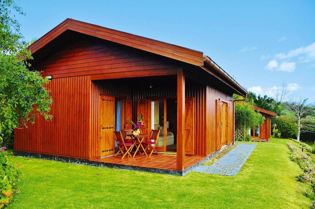 a small red cabin with a table in the yard at Holiday homes Quinta dos Curubás, Vila Franca do Campo in Vila Franca do Campo