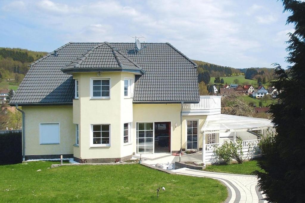 une maison blanche avec un toit noir dans l'établissement Apartment in Fuchsbau, Bad Sachsa, à Bad Sachsa