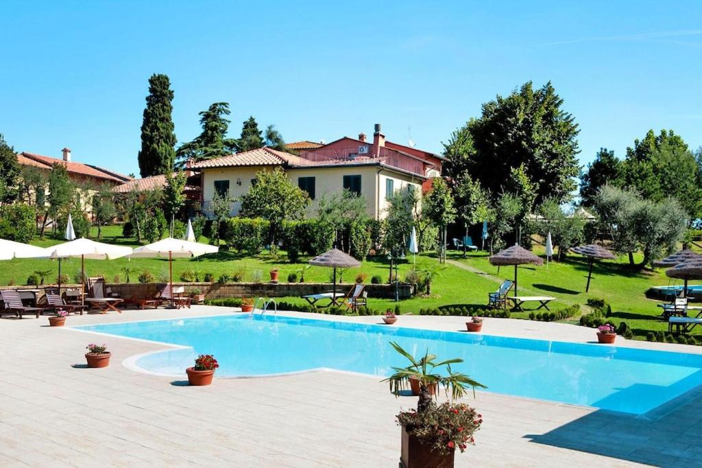 Le Vedute的住宿－Hesse farm holiday Borgo Pinete，一个带桌子和遮阳伞的大型游泳池的度假酒店