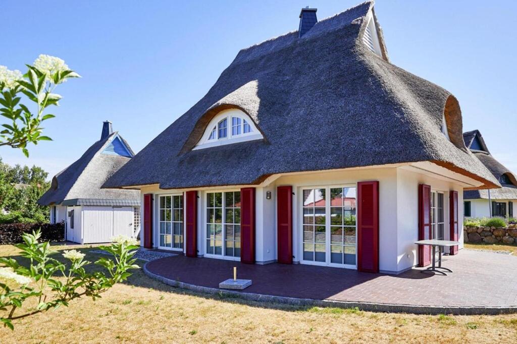 a house with a thatched roof and red doors at Holiday house, Fuhlendorf in Fuhlendorf