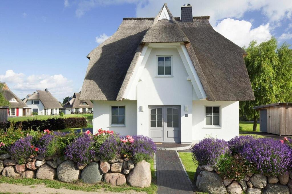 a small white house with a thatched roof at Holiday house, Fuhlendorf in Fuhlendorf