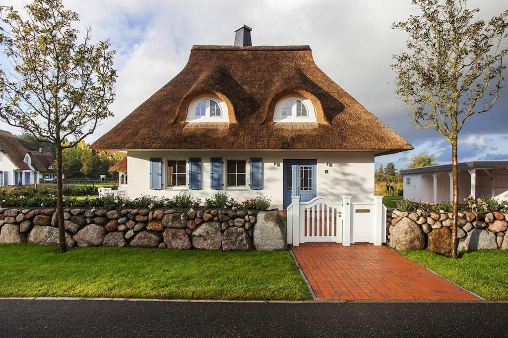 een groot wit huis met een rieten dak bij Holiday house, Fuhlendorf in Fuhlendorf