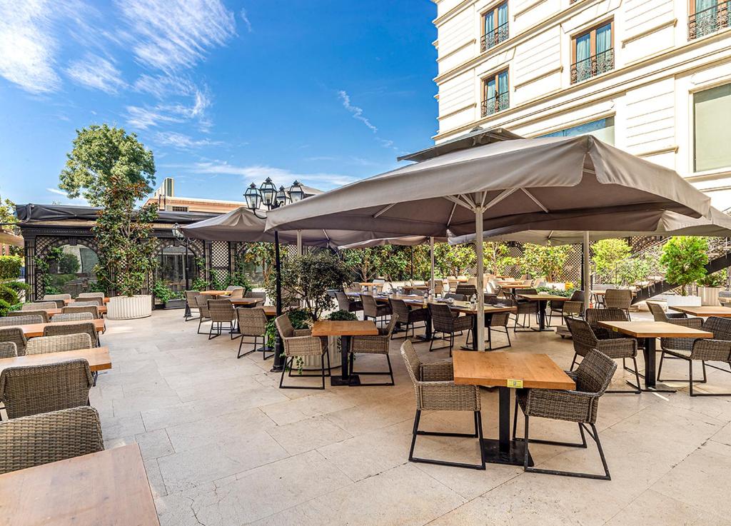 an outdoor patio with tables and chairs and umbrellas at Wyndham Grand Istanbul Kalamış Marina Hotel in Istanbul