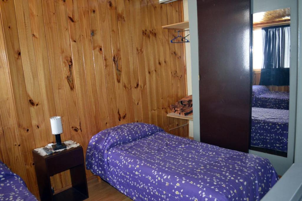 1 dormitorio con 2 camas y pared de madera en Departamentos Muñoz en Río Grande