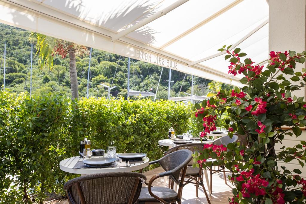 a patio with tables and chairs and flowers at Blue Sail Hotel in Anse Marcel 