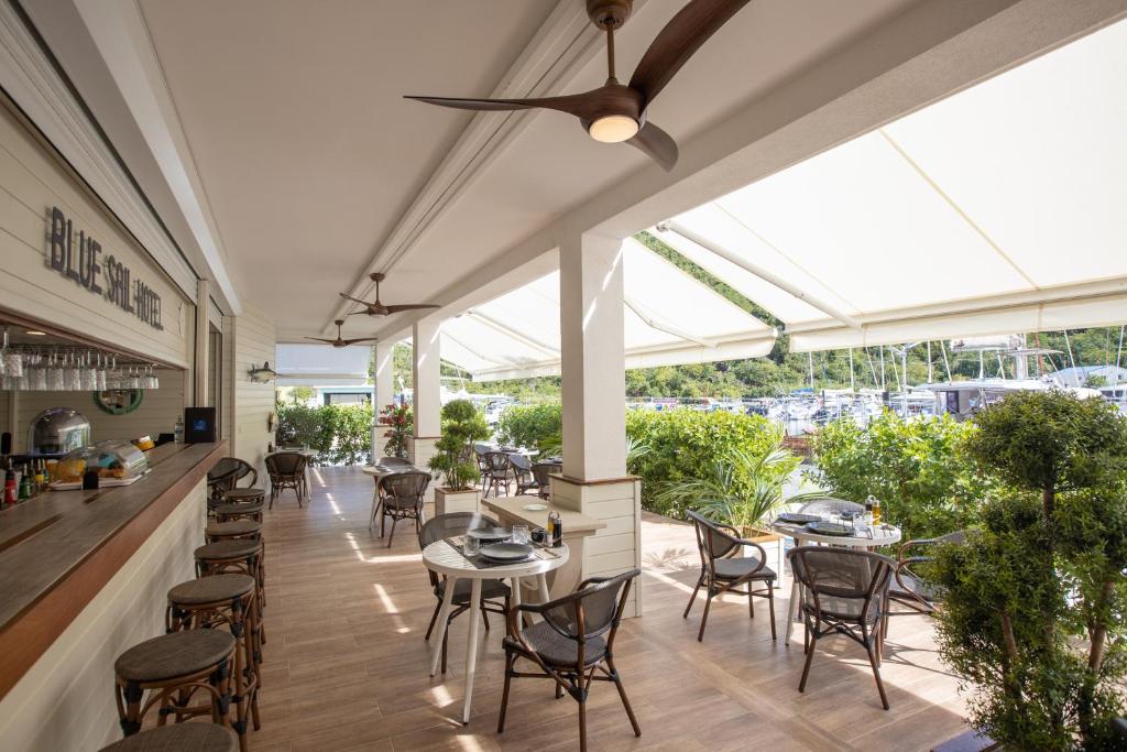 a restaurant with tables and chairs and windows at Blue Sail Hotel in Anse Marcel 