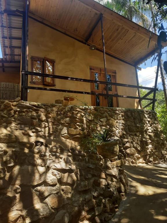 a stone wall in front of a house at Chalé Filhos da Terra in São Francisco Xavier