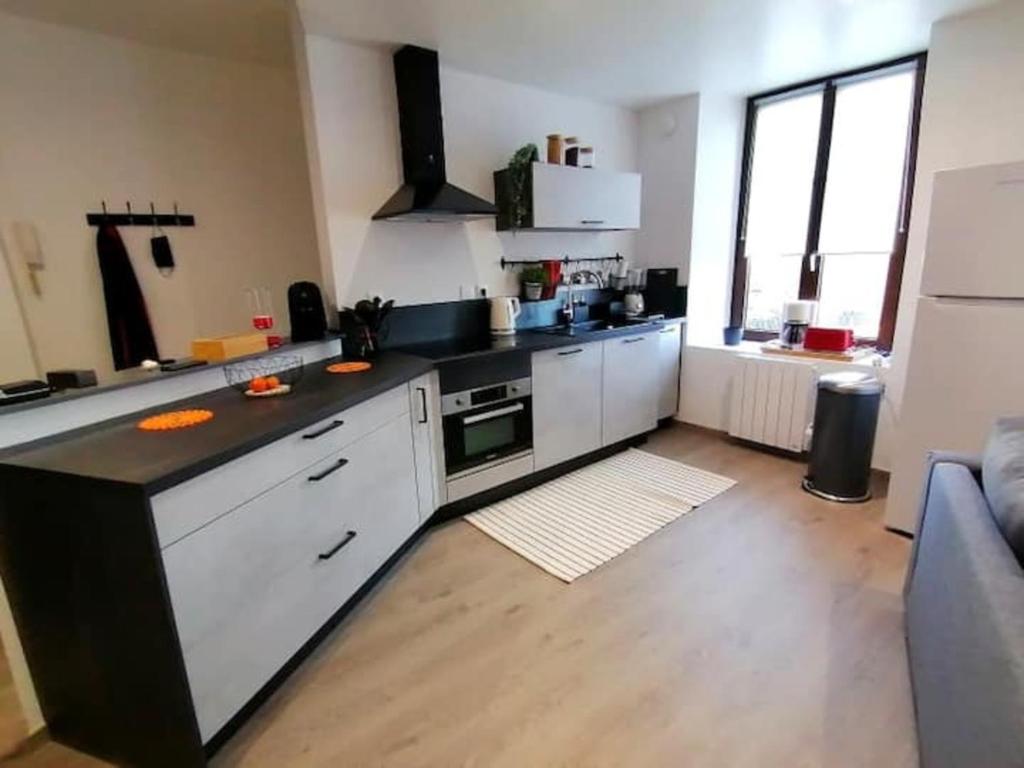 a kitchen with white cabinets and a black counter top at Grand Appartement 2 chambres avec Fibre et Netflix in Belfort