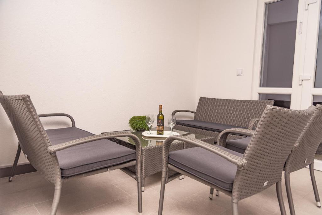 una mesa y sillas con una botella de vino. en Apartmani Marijamagdalena, en Gračac