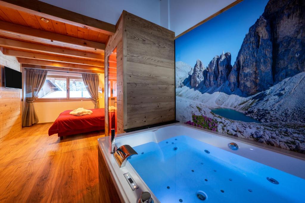 a large tub in a room with a mountain mural at Luxury Chalet Orchidea -SPA Privata in Canazei