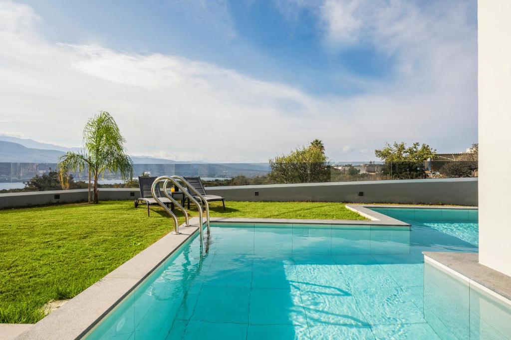 una piscina con vistas a un patio de hierba y a la costa oriental en Villa Jarko en La Canea