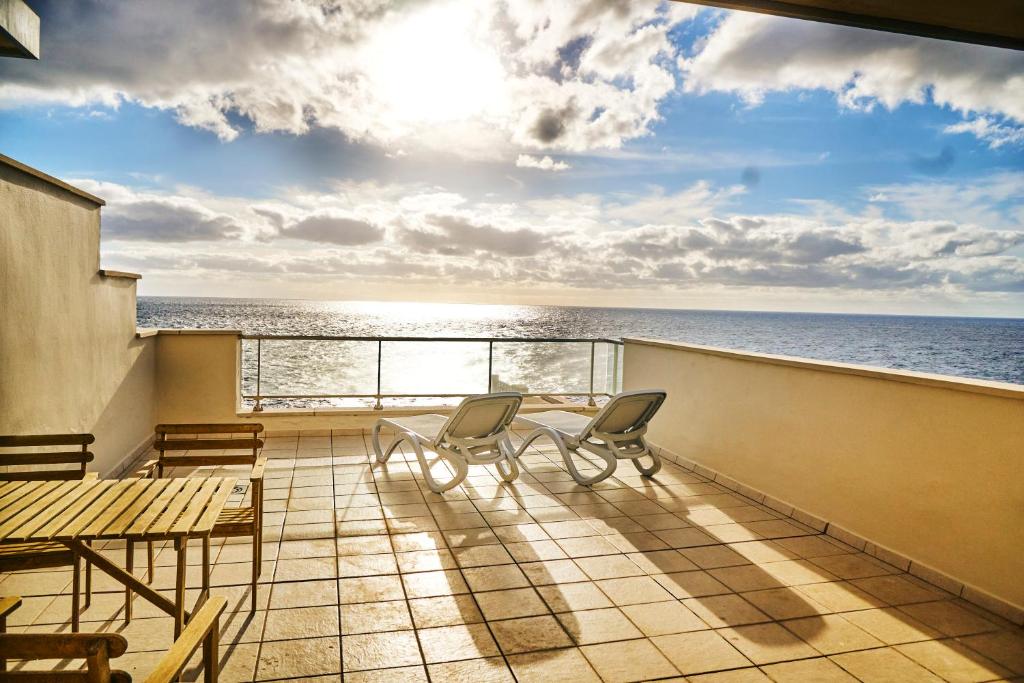 einen Balkon mit Stühlen, einem Tisch und Meerblick in der Unterkunft 3BDR + 2BATH OCEAN VIEW APARTMENT in Santa Cruz de Tenerife