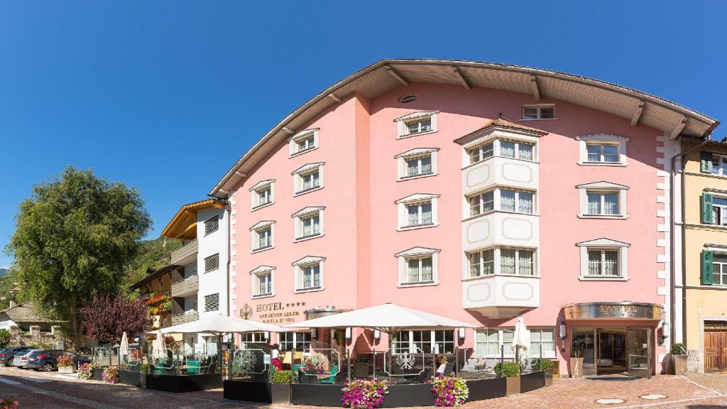 un edificio rosa con sombrillas delante en Cityhotel Goldener Adler B&B en Chiusa