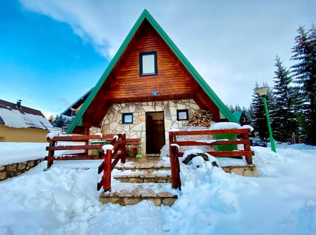 a house with a green roof in the snow at Holiday Home Vojinovic in Žabljak