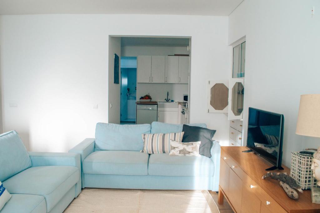 a living room with a blue couch and a television at Xicotina in Moledo