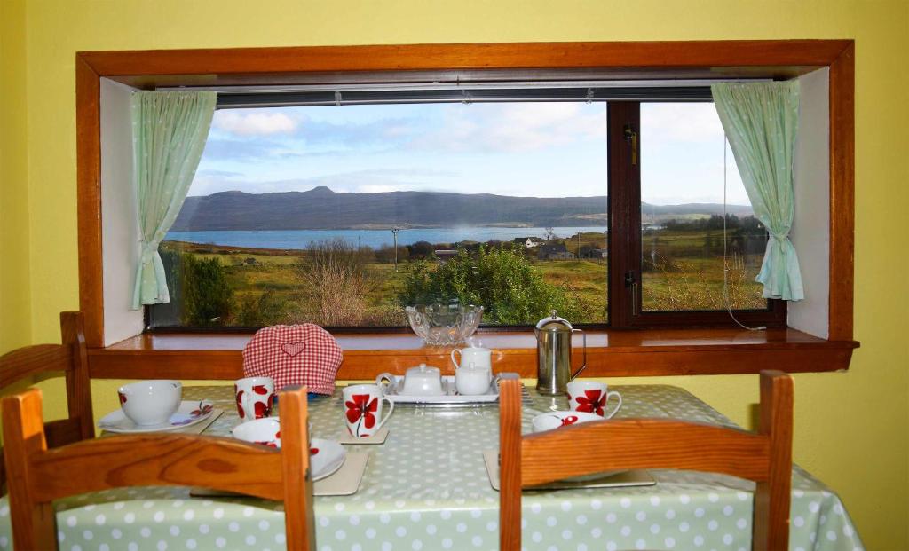 a dining room table with a view of a window at Bramble Cottage in Ollach