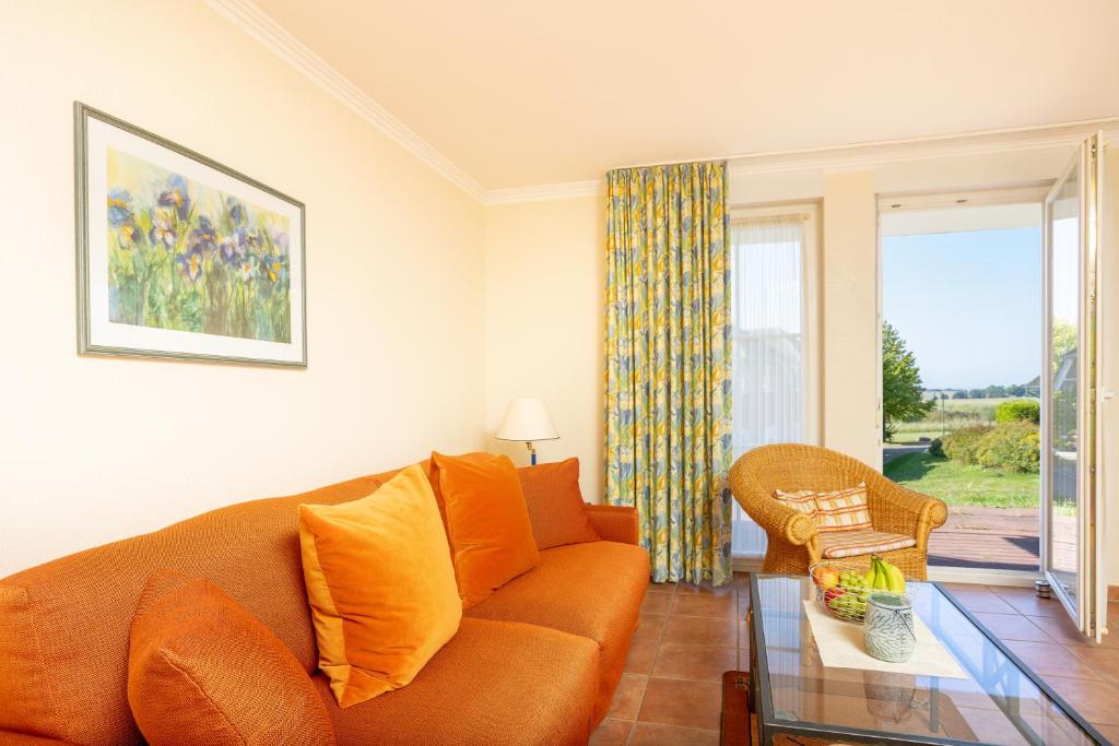 a living room with an orange couch and a glass table at Ferienapartment-ruegen in Neddesitz