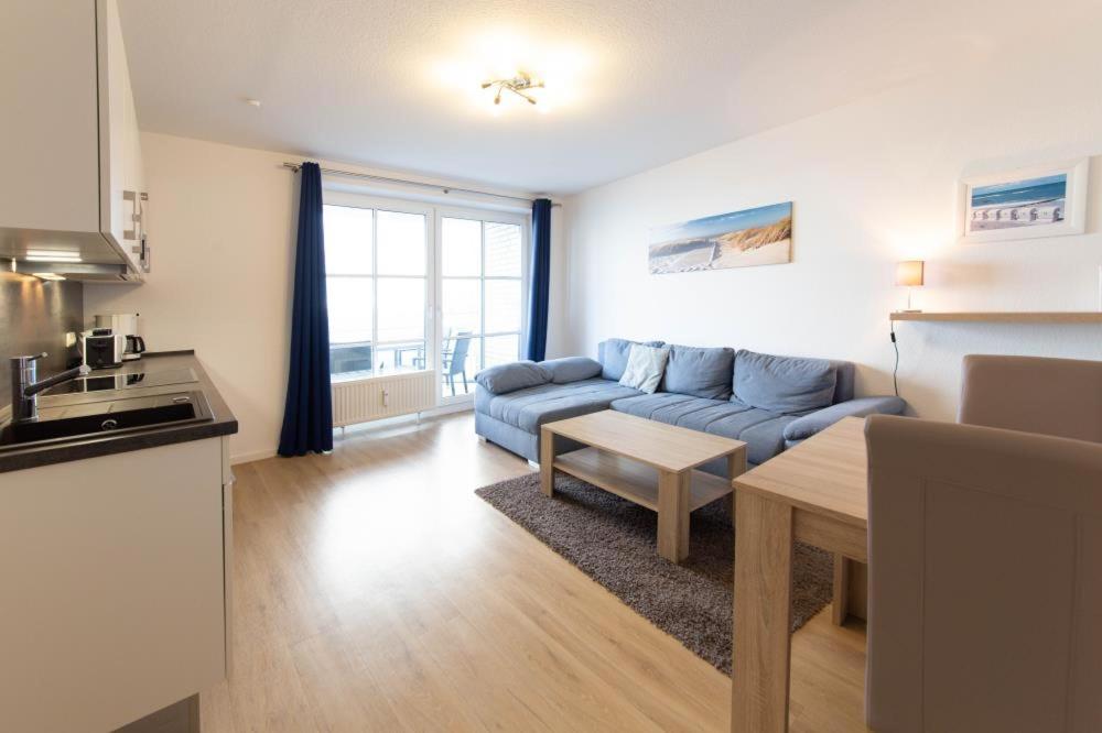 a living room with a blue couch and a table at Ferienwohnung MehrBlick 22 in Niendorf