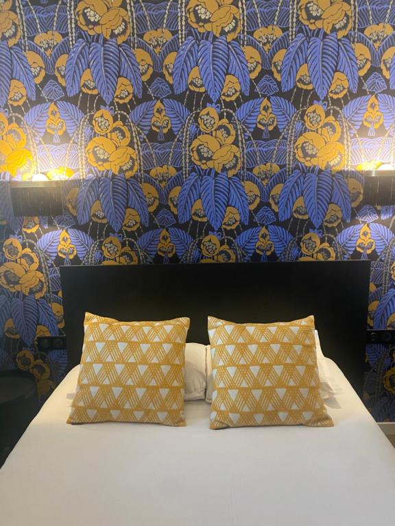 a bed with two pillows in front of a wall at Grand Hotel De La Poste - Lyon Sud - Vienne in Vienne