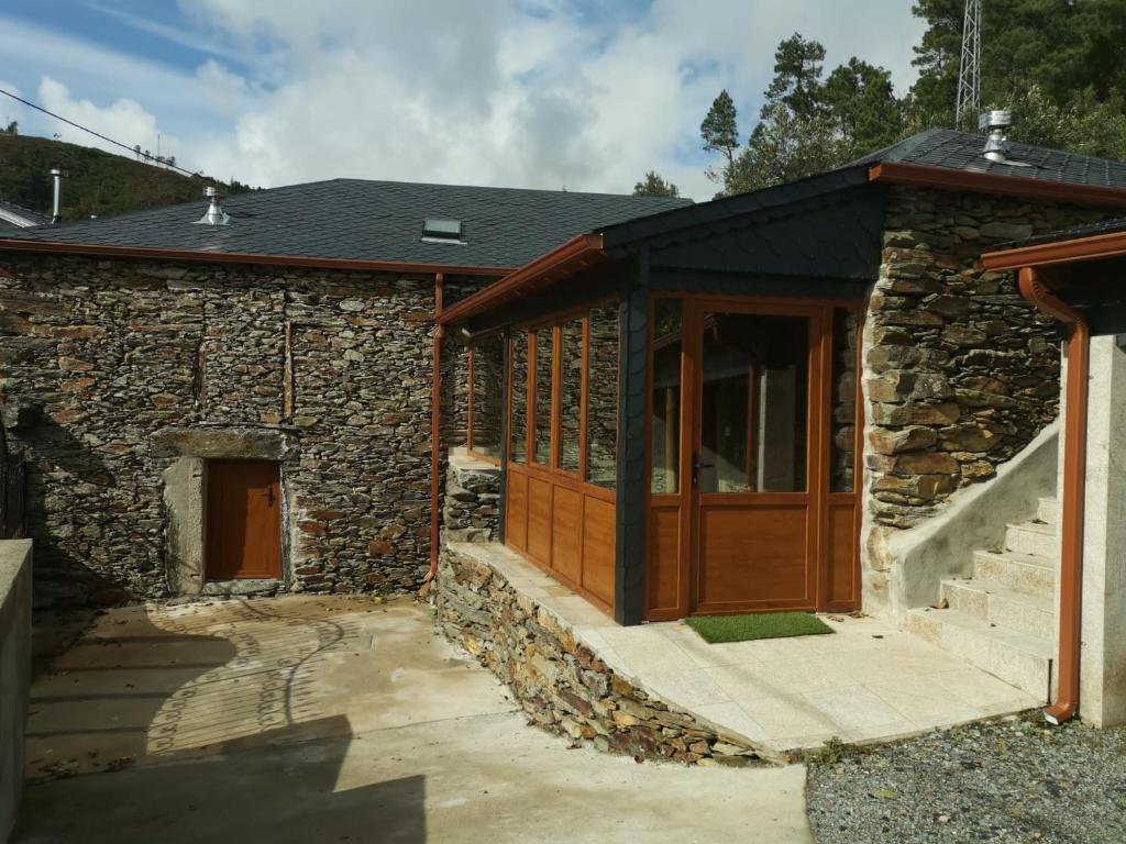 une maison en pierre avec une porte en bois et une terrasse couverte dans l'établissement Casa do Julien Mountain Experience, à Vila Real