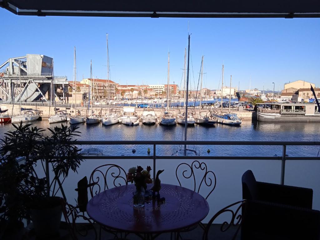een tafel op een balkon met uitzicht op een jachthaven bij Appartement Cosy Terrasse vue Quai Canal + parking in Sète