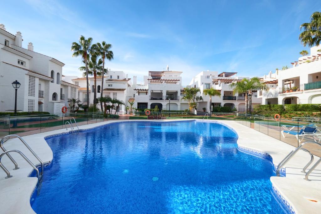 een groot zwembad met stoelen en gebouwen bij Beach Side 2 Bedroom apartment in La Gavia San Pedro in Marbella