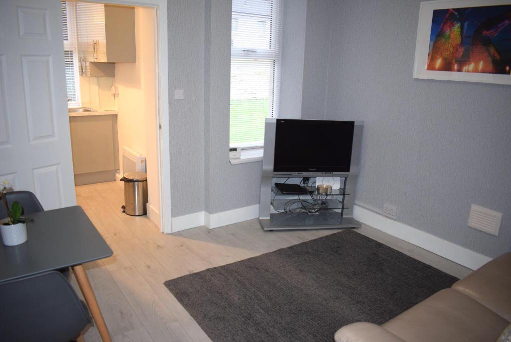 uma sala de estar com uma televisão de ecrã plano no canto em Kelpies Serviced Apartments- Robertson em Falkirk