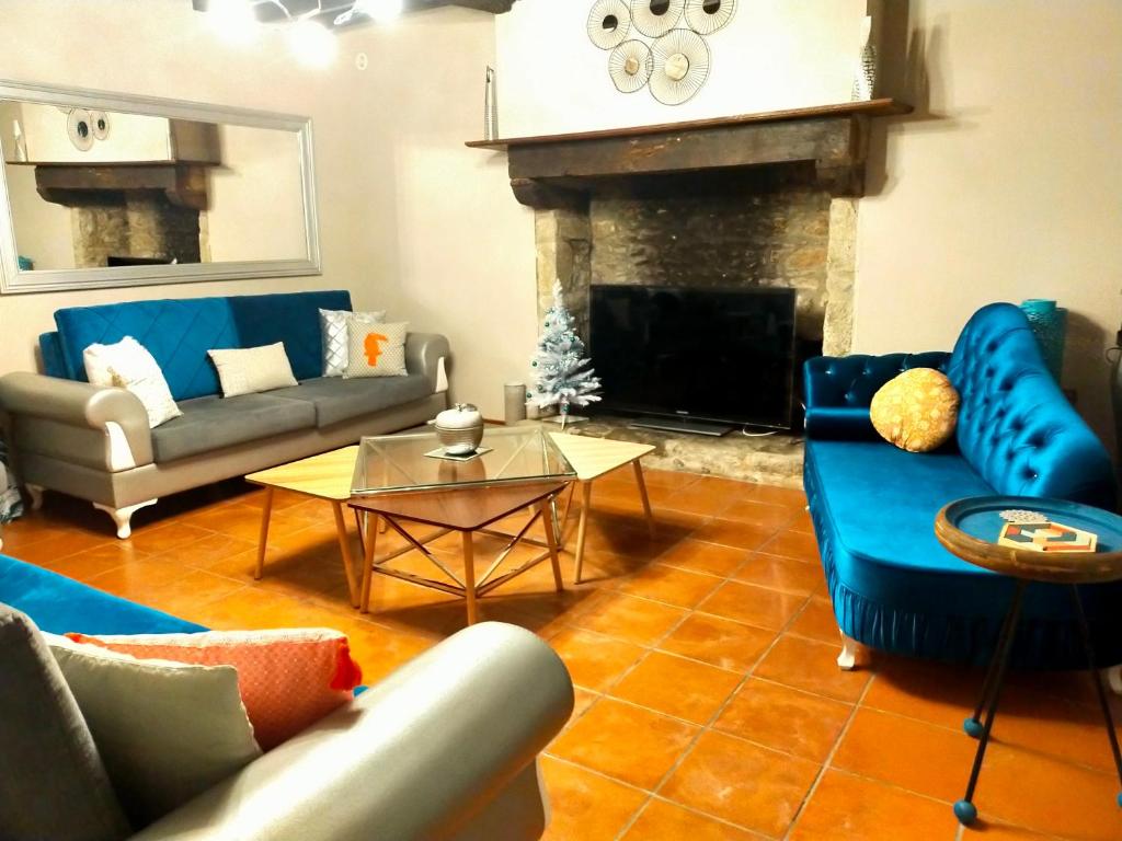 sala de estar con sofás azules y chimenea en Gîte Eloquent, en Gratot